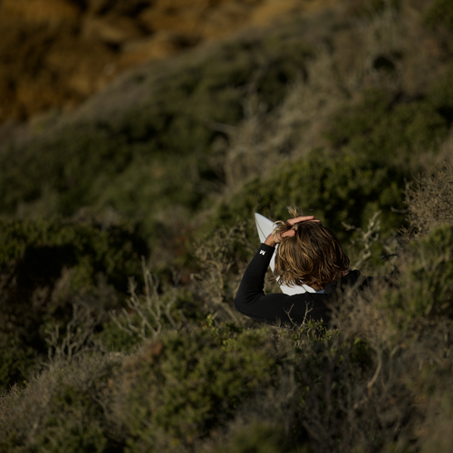 Person resting in coastal scrub on a hillside