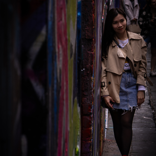 Woman in a doorway beside a graffiti wall