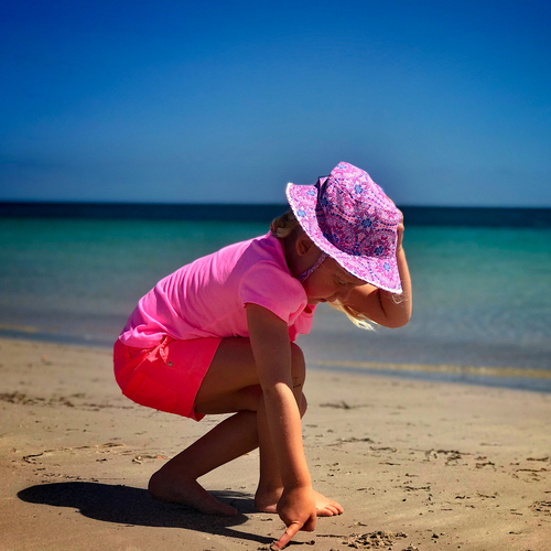 Girl in a pink hat playing on the beach