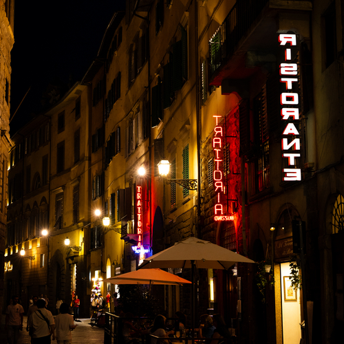 Florence street at night with neon restaurant signs